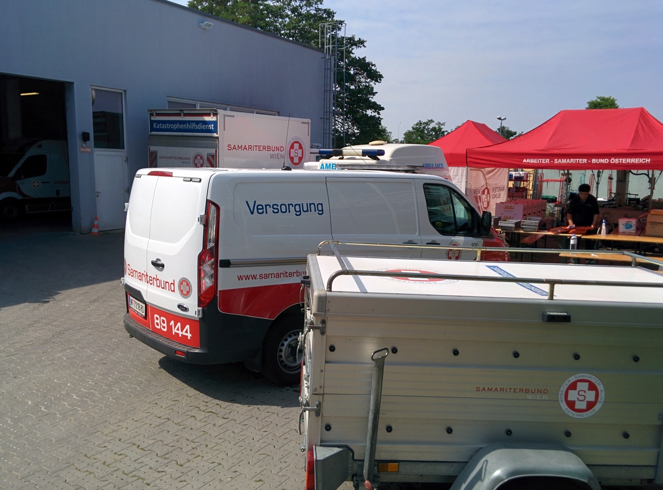 Im Vordergrund ein Anhänger mit Material für den Großschadensfall, dahinter Versorgungsfahrzeuge.