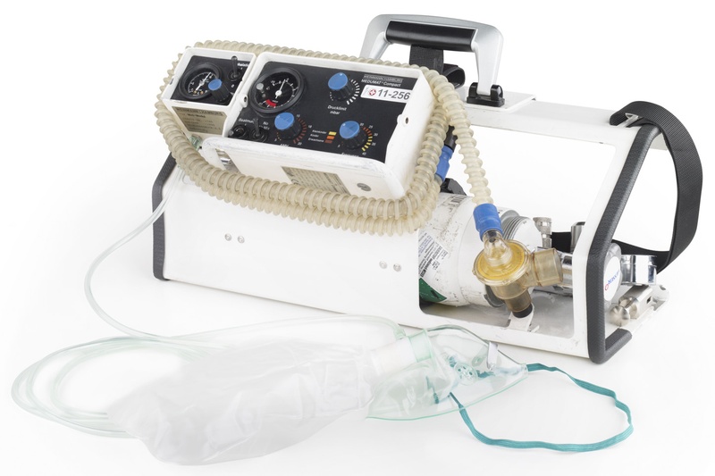 Beatmungsgerät Medumat™ compact auf einer Tragplatte. Zusätzlich angebracht sind eine Sauerstofflasche, eine Berieselungseinheit und daran angeschlossen eine Berieselungsmaske. © Ch. Pallinger, ℓ MfG